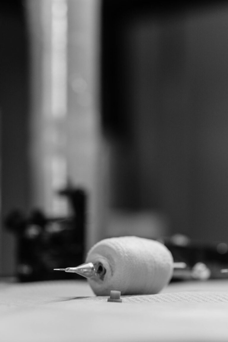 Black and white close-up of a tattoo machine highlighting its precision needle.